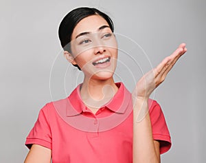 Young beautiful asian woman wore pink t shirt, Showed guide expression ,smile and suggest on gray background