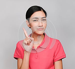 Young beautiful asian woman wore pink t shirt, Showed Pointing and wondering expression , on gray background photo