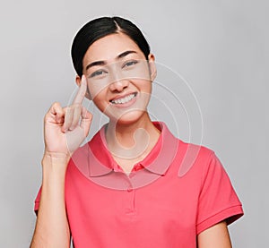 Young beautiful asian woman wore pink t shirt, Showed Thinking expression ,smile on gray background
