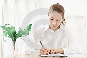 Young Beautiful asian woman wore white shirt Sit and write a book,work  at home