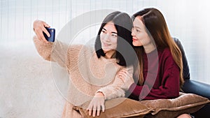 Young beautiful Asian women lesbian couple lover using smartphone selfie together in living room at home with smiling face.Concept