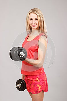 Young beautiful athletic girl holding dumbbells