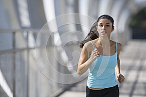 Young beautiful athletic sport woman running and jogging crossing modern metal city bridge