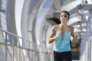 Young beautiful athletic sport woman running and jogging crossing modern metal city bridge