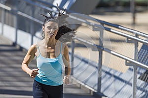 Young beautiful athletic sport woman running and jogging crossing modern metal city bridge