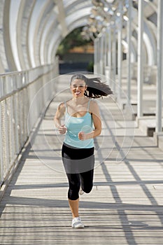 Young beautiful athletic sport woman running and jogging crossing modern metal city bridge