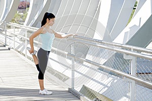Young beautiful athletic sport woman stretching after running crossing modern metal city bridge