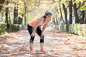 Attractive sport woman in runner sportswear breathing gasping and taking a break tired and exhausted after running workout on Autu