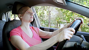 Young beautiful bald woman in sunglasses sitting at the wheel of a car on a summer day. car trip