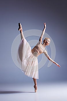 Young beautiful ballerina dancer dancing on a studio background