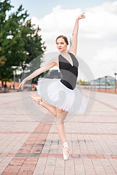 Young and beautiful ballerina posing on the street.