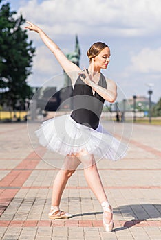 Young and beautiful ballerina posing on the street.