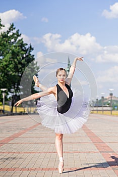 Young and beautiful ballerina posing on the street.