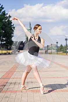 Young and beautiful ballerina posing on the street.