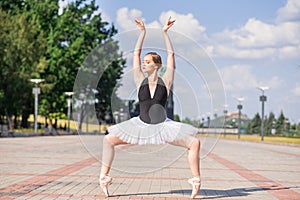 Young and beautiful ballerina posing on the street.