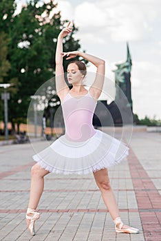 Young and beautiful ballerina posing on the street.