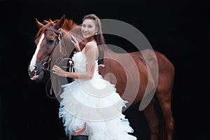 Young beautiful beauty bride in fashion white bridal wedding costume stand by handsome horse on black background