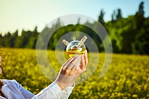 A young beautiful biologist or agronomist examines the quality of rapeseed oil on a rape field. Agribusiness concept