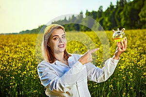 A young beautiful biologist or agronomist examines the quality of rapeseed oil on a rape field. Agribusiness concept