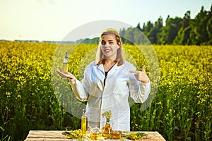 A young beautiful biologist or agronomist examines the quality of rapeseed oil on a rape field. Agribusiness concept