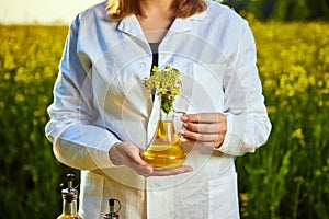A young beautiful biologist or agronomist examines the quality of rapeseed oil on a rape field. Agribusiness concept