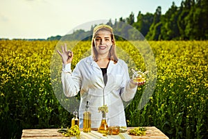 A young beautiful biologist or agronomist examines the quality of rapeseed oil on a rape field. Agribusiness concept