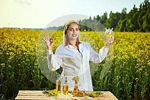 A young beautiful biologist or agronomist examines the quality of rapeseed oil on a rape field. Agribusiness concept