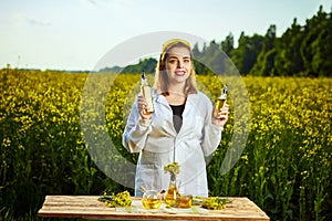 A young beautiful biologist or agronomist examines the quality of rapeseed oil on a rape field. Agribusiness concept