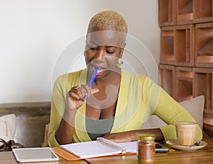 Young beautiful black African American business woman working at coffee shop smiling happy taking notes in notepad using digital t