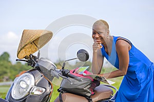Young beautiful black afro american tourist woman with scooter motorbike looking to road map searching the way exploring fields in