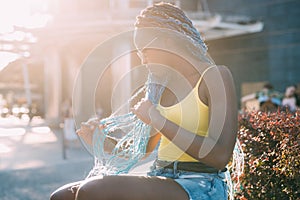 Young beautiful black woman sititng alone outdoor backlight pensive