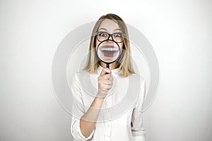 Young beautiful blond woman holding magnifier near her mouth isolated white background