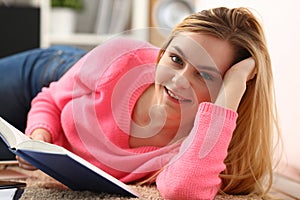 Young beautiful blond woman lie on the floor read book