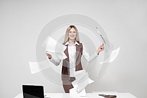 Young beautiful blond woman in an office suit on a white background. Scatters documents.