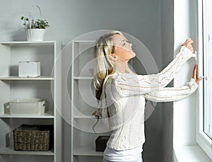 Young and beautiful blond woman opening the window