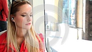 Young beautiful blond woman riding tram, listening to music and dancing