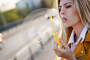 Young beautiful woman using bubble blower in the city