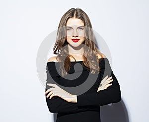 Young beautiful blond woman wearing black dress posing over white background