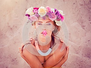 Young beautiful blonde bride in a wreath posing on the beach