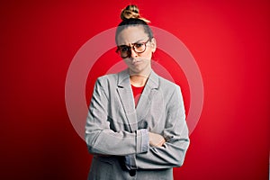 Young beautiful blonde businesswoman with blue eyes wearing glasses and jacket skeptic and nervous, disapproving expression on