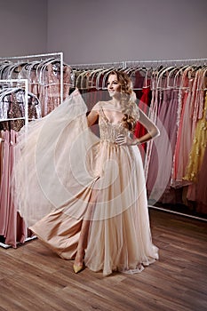 Young beautiful blonde girl wearing a full-length beige yellow champaign chiffon slit prom ball gown decorated with