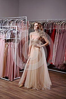 Young beautiful blonde girl wearing a full-length beige yellow champaign chiffon slit prom ball gown decorated with