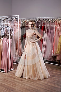 Young beautiful blonde girl wearing a full-length beige yellow champaign chiffon slit prom ball gown decorated with