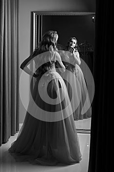 Young beautiful blonde girl wearing a full-length pink violet or purple chiffon prom ball gown decorated with sparkles