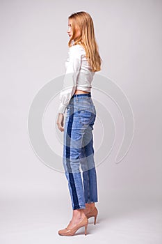 Young beautiful blonde girl in a white shirt. Studio gray isolated background