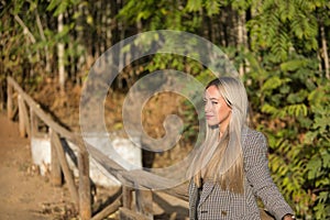 Young, beautiful, blonde, green-eyed woman leaning on a wooden railing, relaxed and gazing into infinity. Concept beauty, fashion