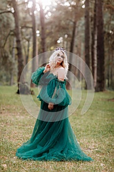 Young beautiful blonde hair woman queen. Princess walks. autumn green forest mystic. Vintage medieval shiny crown. Long evening