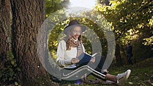 Young beautiful blonde hair woman reading book in the city park.