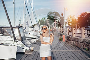 Young beautiful woman staying near yachts in harbor
