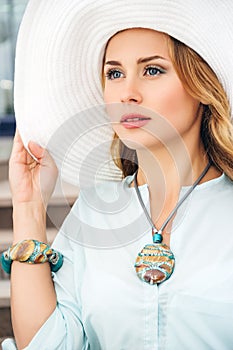 Young beautiful blonde in jewelry and in big white hat